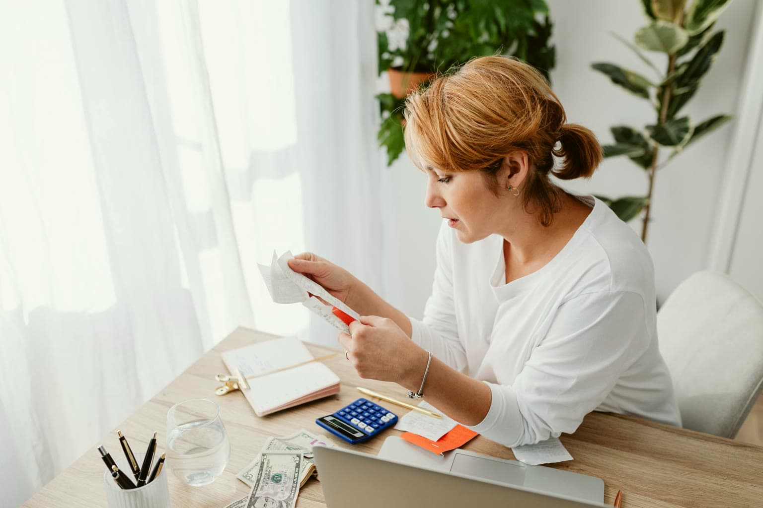 Business owner sorting receipts at a bright desk with a calculator