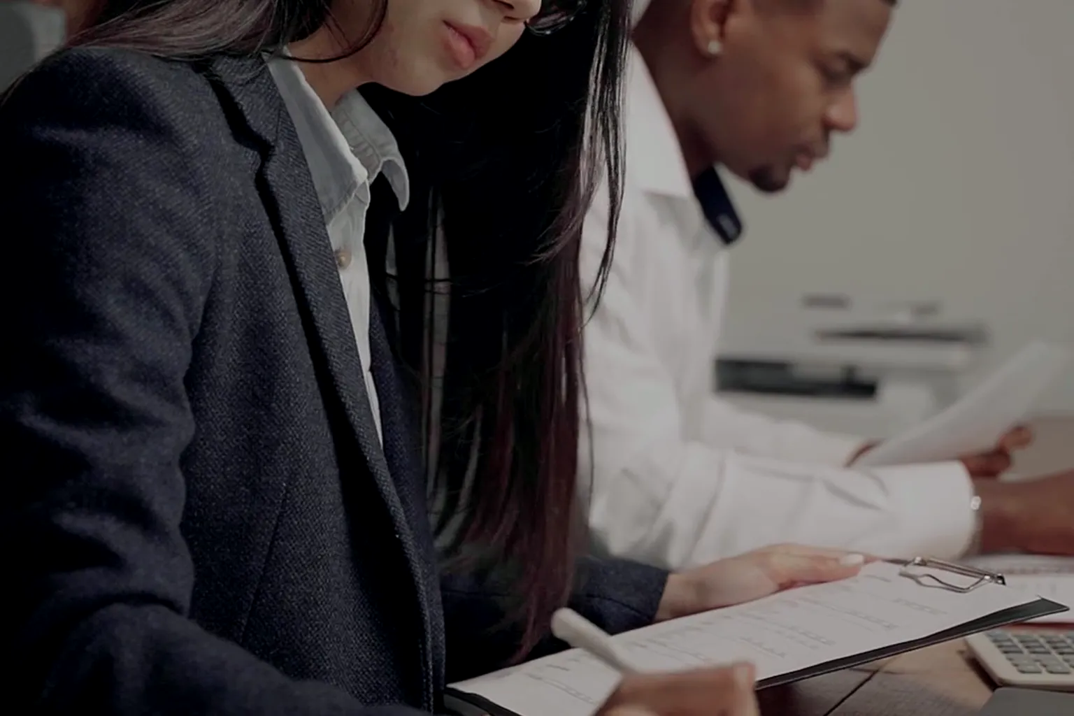 Small-business owner and accountant reviewing a 2026 year-end profit and cash forecast on a desk calculator and ledger